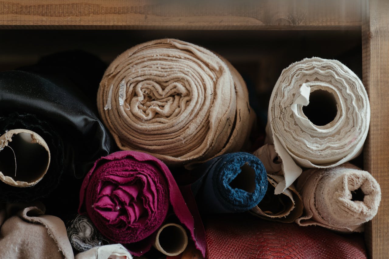 services-02 A selection of vibrant fabric rolls neatly arranged in a textile workshop setting indoors.